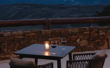 Bar seating at Amangani at dusk, overlooking snow-capped mountains and valley lights below.