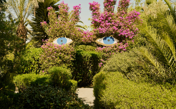 安缦珍纳度假村的花园小径，两旁种植着棕榈树和盛开的洋红色花卉。