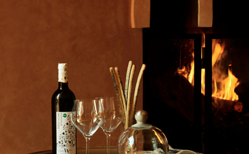 安缦珍纳度假村欢迎饮品，玻璃桌上摆放葡萄酒瓶和酒杯，背景为摩洛哥风格的拱形门廊。