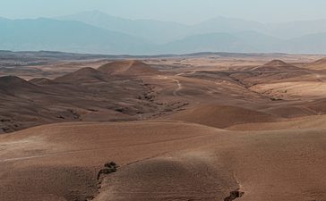 安缦珍纳度假村阿加弗沙漠广阔的沙丘景观，远处山峦在雾霭中若隐若现。