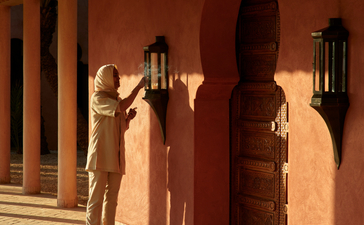 宾客在安缦珍纳度假村的摩洛哥建筑前驻足观赏,晚间光线投出长长的影子。