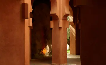 Lobby with bassin at Amanjena resort, Morocco, terracotta arches and warm lighting.