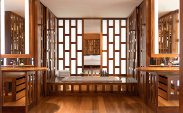 Salle de bains du pavillon Amanpuri avec portes à carreaux en bois et mobilier en teck.