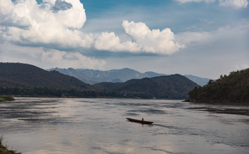 Mekong River landscape at Amantaka, with mountains and clouds reflected in calm waters.