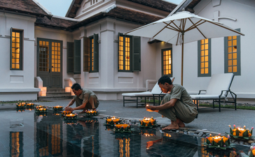 Guests conversing by the reflecting pool at Amantaka, a colonial-era property in Laos.