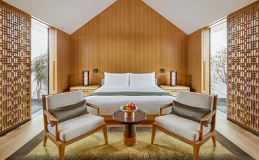 Amanyangyun principal bedroom with symmetrical wooden panelling, blue bedding, and mid-century chairs.