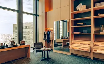 Aman Essentials boutique retail space at Aman Tokyo hotel, featuring wooden shelving, floor-to-ceiling windows overlooking the city, and curated homeware displays.