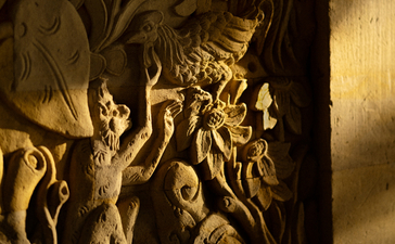 Ornate stone relief carving illuminated by warm light at Amandari resort in Bali, Indonesia.