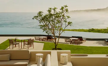 Amanera resort pool terrace overlooking the Caribbean Sea with lounge chairs and a solitary tree on manicured lawn.