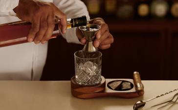 Cocktail being prepared at Amanera resort's lounge bar, with bartender pouring spirit into a glass.