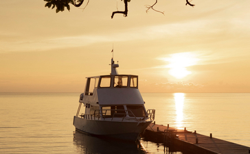 传统木制渔船停靠在码头，安缦湾澜度假村，印度尼西亚松巴岛，日落时分。