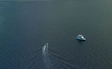 Aerial view of a speedboat approaching a small forested island in Saleh Bay, Sumbawa, Indonesia, where Amanwana is located.
