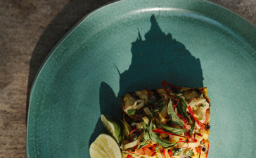 安缦湾澜度假村中新鲜海鲜料理，盘中展示烤鱼配柠檬和蔬菜。