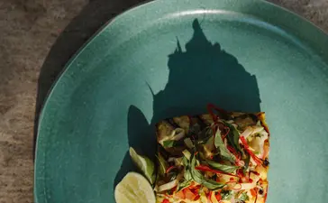 Grilled seafood fillet with lime and vegetables on a turquoise plate at Amanwana, Sumbawa, Indonesia.