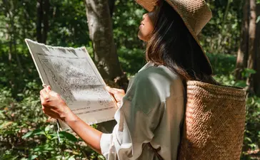 Woman with woven backpack studying a map during a treasure hunt at Amanwana, Sumbawa, Indonesia.