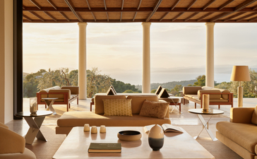 Villa living area at Amanzoe with wooden beams, terracotta furnishings, and Aegean views.
