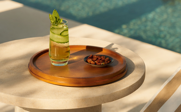 Piatto in legno con bottiglia di profumo e decorazioni, restaurant spiaggia Amanzoe.