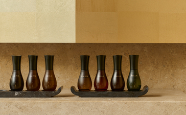 Flaconi di prodotti spa Aman Essentials esposti su una mensola di pietra ad Amanzoe resort.