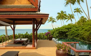 Deluxe ocean pool pavilion exterior at Amanpuri, Thailand, with wooden structure overlooking tropical gardens and sea view.