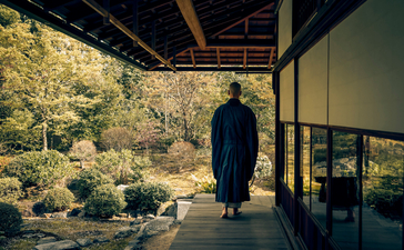 Ospite in contemplazione su una veranda con vista sul giardino zen di Aman Kyoto.