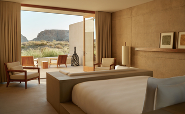 Amangiri Suite with bed facing expansive desert landscape view through floor-to-ceiling windows.