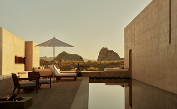 Amangiri suite terrace at sunset with lounge seating overlooking desert landscape and still water.