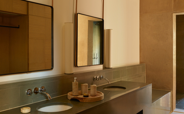 Amangiri suite bathroom with warm timber cabinetry and dual vanity sinks.