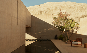 Amangiri suite with angular rammed-earth walls, desert landscape, and solitary tree casting shadows.