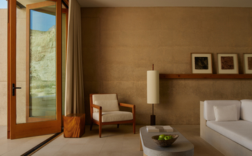 Girijaala Suite bedroom at Amangiri resort with warm earth tones, floor-to-ceiling glass door and minimalist furnishings.
