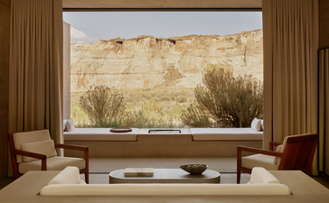 Mesa pool suite at Amangiri resort with floor-to-ceiling window overlooking desert landscape, featuring mid-century seating.