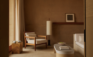Mesa Pool Suite bedroom at Amangiri resort, with warm terracotta walls and minimalist furnishings bathed in natural light.