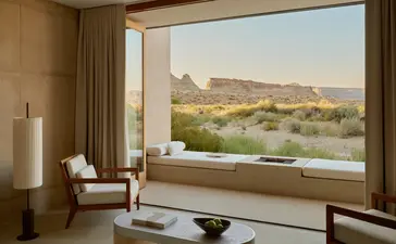 Amangiri resort desert pool suite with floor-to-ceiling window overlooking arid landscape and mountains.