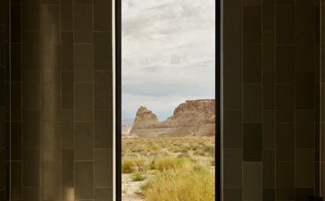 Freestanding bathtub positioned before a tall window framing desert mesa views at Amangiri.
