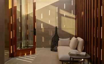 Orchard Suite sitting area at Amangiri with warm lighting, wooden screens, and desert views through floor-to-ceiling windows.