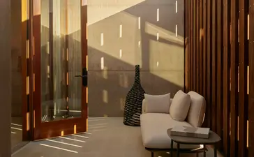 Orchard Suite sitting area at Amangiri with warm lighting, wooden screens, and desert views through floor-to-ceiling windows.