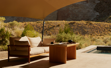 Breakfast pavilion at Amangiri with wooden seating, white cushions, and desert landscape views.