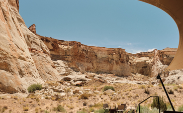Wooden bench facing plunge pool at Amangiri pavilion, framed by canyon rock formations under clear sky.