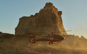 Jeep parked beneath towering rock formation at Amangiri resort, Utah desert at sunset.