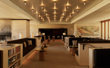 Amangiri library with warm lighting, wooden shelving, grand piano, and open reading spaces.