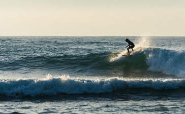 Surfer riding a wave at Amanwella's beach in Sri Lanka.