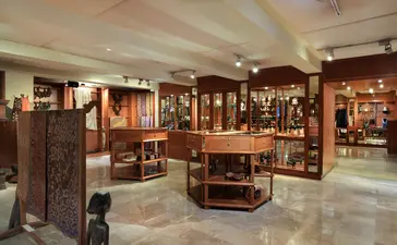 Boutique room at Amandari in Ubud with warm wooden furnishings and display cases.