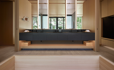 Minimalist reception desk at Aman Kyoto with clean lines and warm wood tones beneath high ceilings.