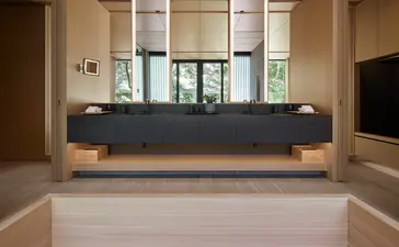 Réception minimaliste d'Aman Kyoto avec comptoir noir et baies vitrées.