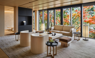 Spa treatment room at Aman Kyoto with floor-to-ceiling windows overlooking autumn foliage and minimalist wooden furnishings.