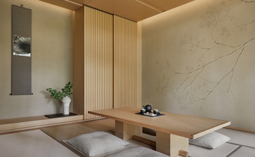 Minimalist bedroom at Aman Kyoto with natural wood panelling, tatami mat flooring, and subtle built-in furnishings.