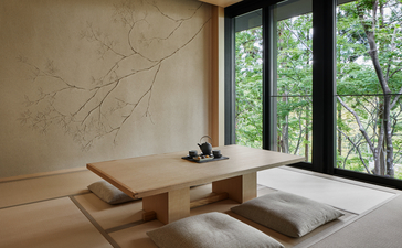 Minimalist accommodation interior at Aman Kyoto with wooden platform bed, natural light from garden views, and calm aesthetic.