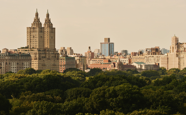 Aman New York's exterior with Central Park trees and Manhattan skyline view.