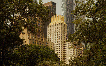 Art Deco skyscraper framed by trees at Aman New York