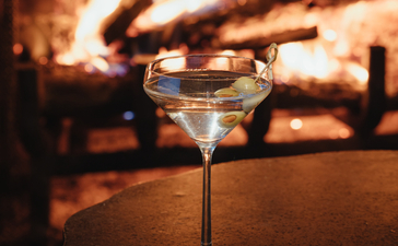 Cocktail glass on table with fireplace glowing in background at Amangani.