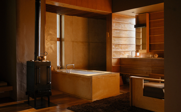 Wooden bathroom suite at Aman Bhutan featuring a soaking tub, mirror and vanity in warm timber tones.